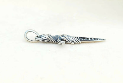 Silver pendant with intricate design on a white background