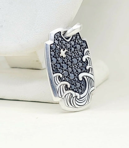 A sterling silver pendant featuring a wave design with a dark, textured starry sky background, displayed on a white jewelry stand.