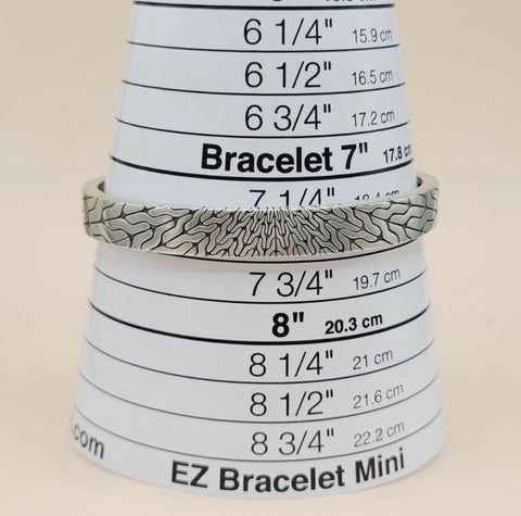 A silver bracelet with a textured, wavy patterned design, displayed on a white cone-shaped sizing tool labeled 'EZ Bracelet Mini'.