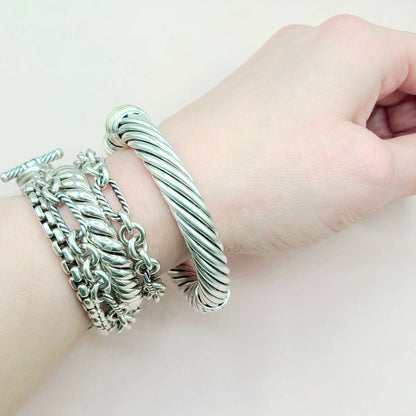 Silver bracelets on a wrist against a light background