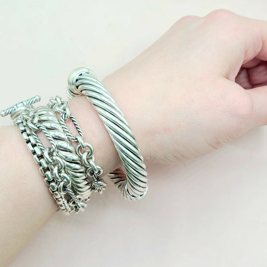 Silver bracelets on a wrist against a light background